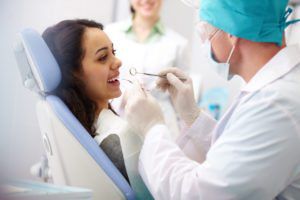 female patient sitting in dental chair smiling and talking to the dentist
